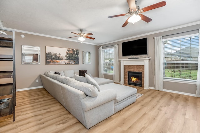 living room featuring light hardwood / wood-style floors, crown molding, and a tiled fireplace