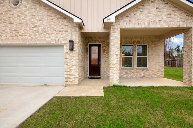 view of exterior entry with a garage and a lawn