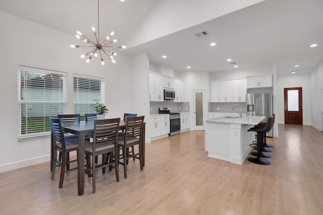 dining area with an inviting chandelier, sink, and light hardwood / wood-style floors