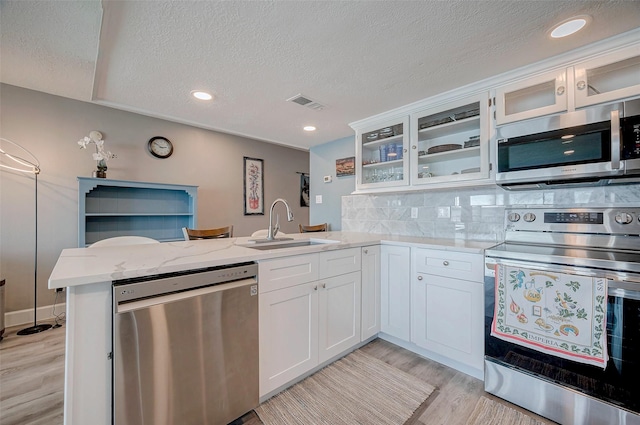 kitchen with a sink, visible vents, white cabinets, appliances with stainless steel finishes, and glass insert cabinets