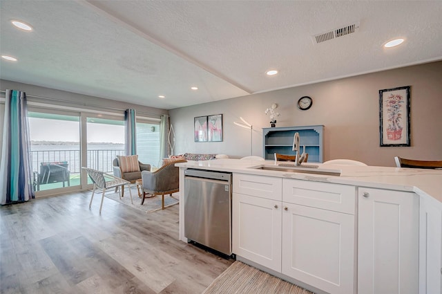 kitchen with light stone counters, visible vents, white cabinetry, open floor plan, and stainless steel dishwasher