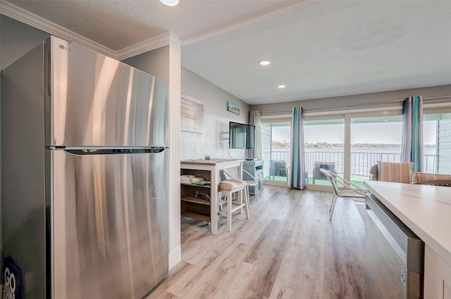 kitchen with stainless steel appliances, light countertops, a textured ceiling, and light wood finished floors