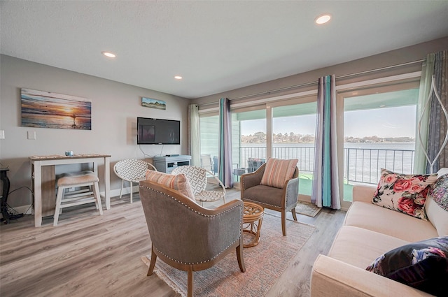 living room with light wood-style floors, baseboards, and recessed lighting