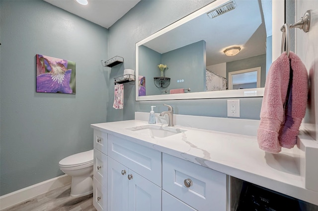 bathroom with visible vents, toilet, vanity, wood finished floors, and baseboards