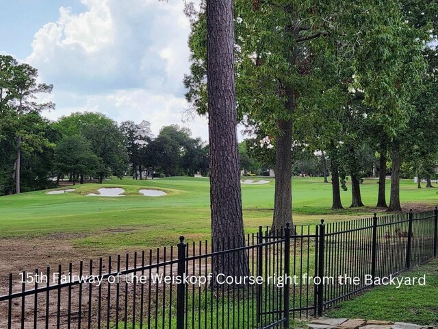 view of property's community featuring a yard, fence, and golf course view