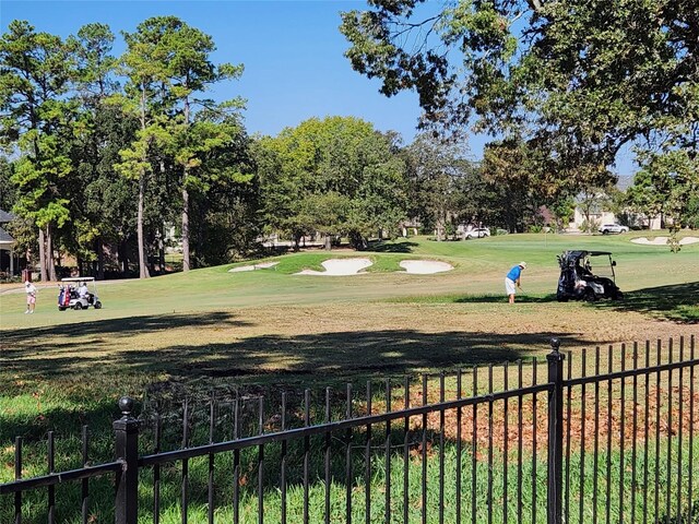 view of home's community with a yard, golf course view, and fence