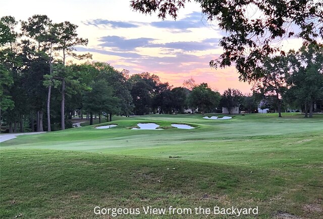 view of community featuring view of golf course and a yard