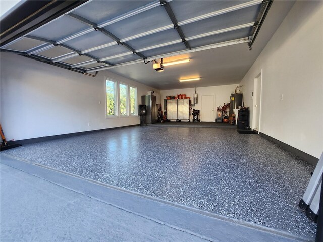 garage with baseboards, freestanding refrigerator, electric water heater, and a garage door opener