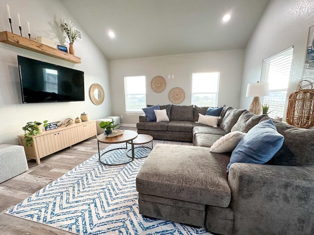 living room with high vaulted ceiling and light wood-type flooring