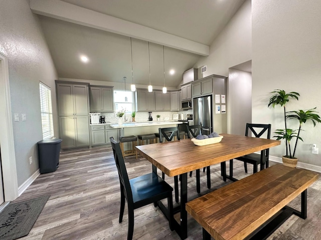 dining area with beamed ceiling, high vaulted ceiling, and light hardwood / wood-style flooring