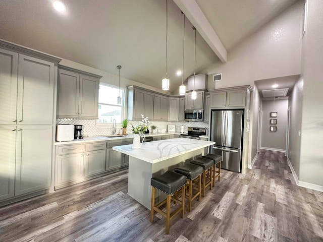 kitchen featuring sink, a breakfast bar area, appliances with stainless steel finishes, hanging light fixtures, and a center island