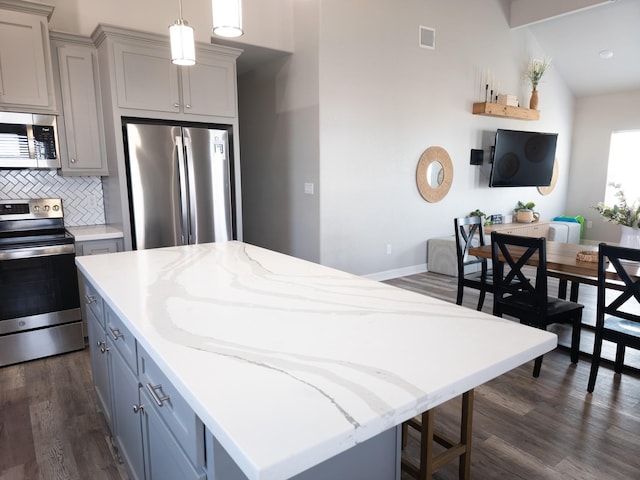 kitchen with tasteful backsplash, decorative light fixtures, gray cabinets, and stainless steel appliances