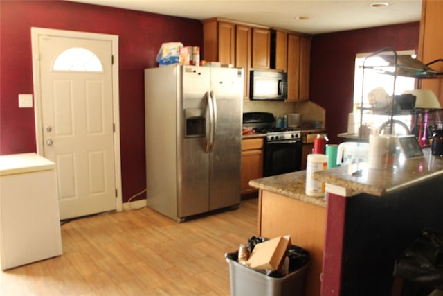 kitchen featuring stainless steel fridge with ice dispenser, light hardwood / wood-style flooring, gas stove, and kitchen peninsula