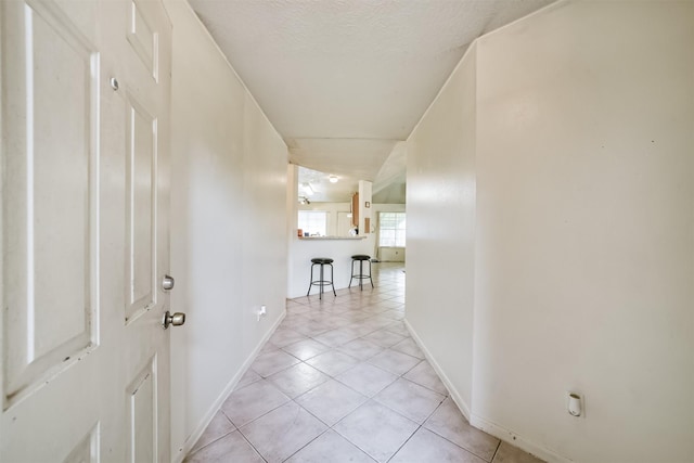 corridor with light tile patterned floors and a textured ceiling