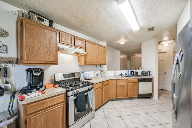 kitchen with appliances with stainless steel finishes, a textured ceiling, and light tile patterned floors