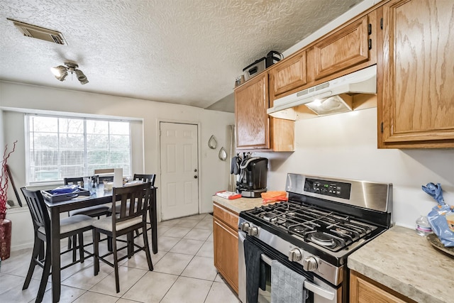 kitchen with light tile patterned flooring, stainless steel range with gas cooktop, and a textured ceiling