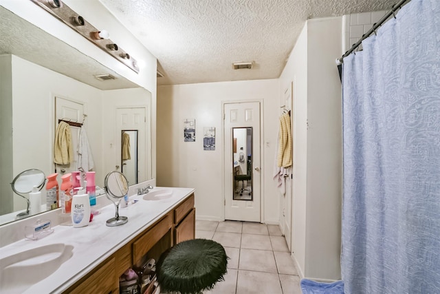 bathroom featuring tile patterned flooring, vanity, a textured ceiling, and walk in shower