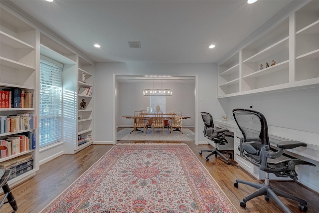 office with hardwood / wood-style flooring, an inviting chandelier, and built in features