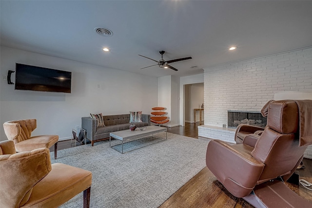 living room featuring ceiling fan, a brick fireplace, and dark hardwood / wood-style flooring