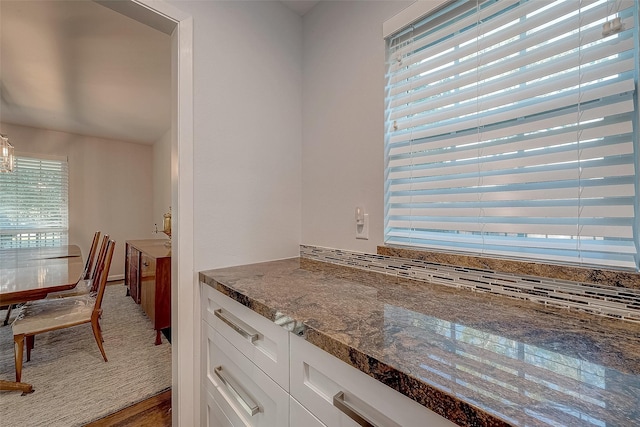 kitchen featuring white cabinetry, dark stone counters, and tasteful backsplash