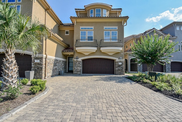 view of front of house with stone siding, a tile roof, a balcony, and stucco siding