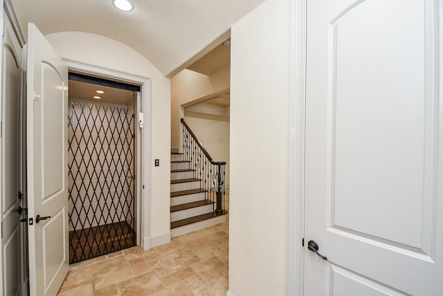 interior space with stairs, lofted ceiling, stone finish floor, and recessed lighting