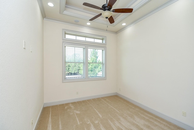 spare room with ornamental molding, a tray ceiling, light carpet, and baseboards