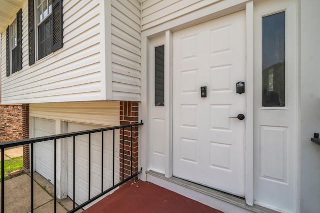 property entrance featuring a garage and brick siding