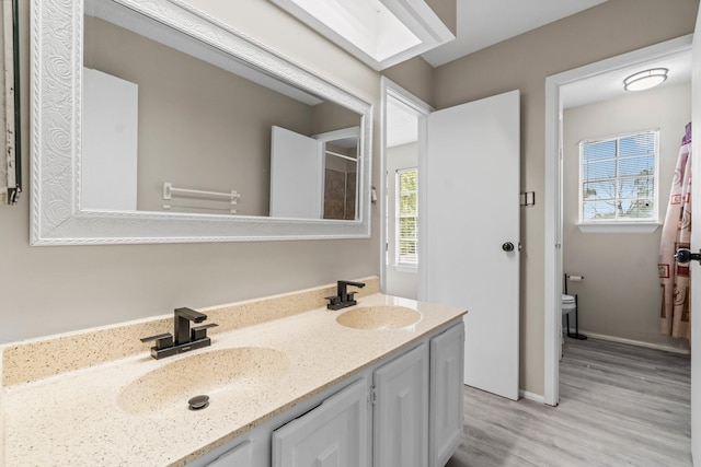 bathroom with double vanity, wood finished floors, toilet, and a sink