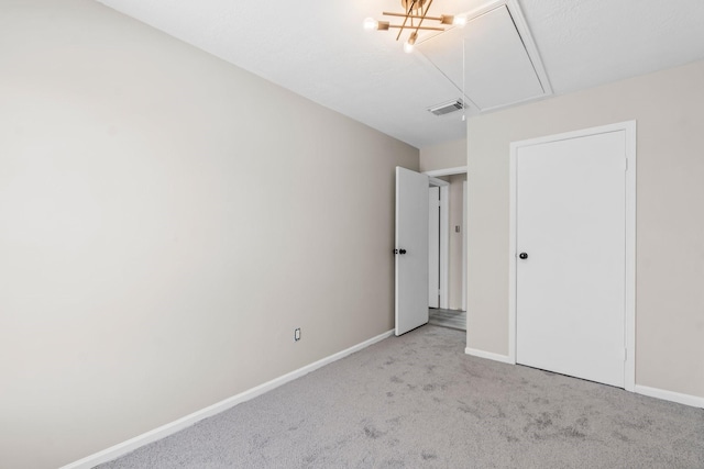 unfurnished bedroom featuring attic access, baseboards, visible vents, and carpet floors