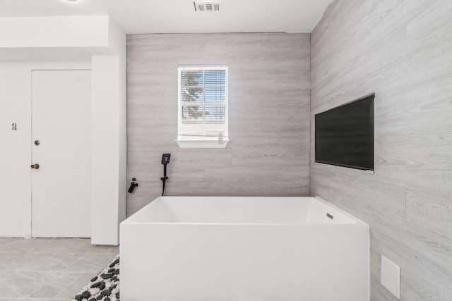 bathroom with a freestanding tub and visible vents