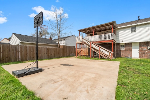 exterior space with stairway, fence, a wooden deck, a lawn, and brick siding