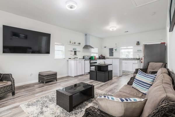 living room with a healthy amount of sunlight, sink, and light hardwood / wood-style flooring