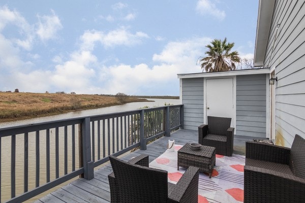 wooden terrace featuring outdoor lounge area, a storage unit, and a water view