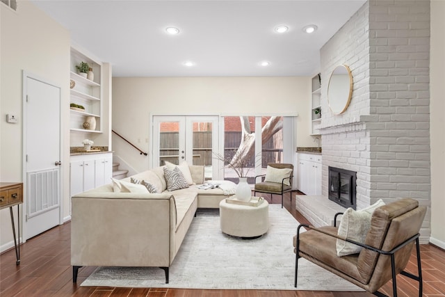 living room featuring french doors, built in shelves, hardwood / wood-style floors, and a brick fireplace