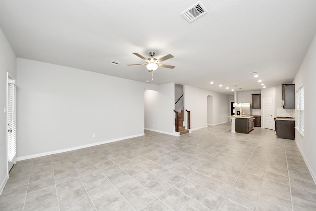 unfurnished living room featuring light tile patterned flooring and ceiling fan