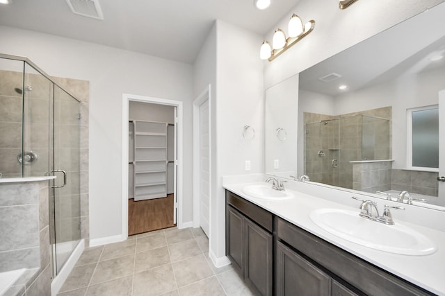 bathroom with a shower with door, vanity, and tile patterned flooring