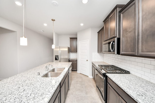 kitchen featuring appliances with stainless steel finishes, pendant lighting, tasteful backsplash, sink, and light stone countertops