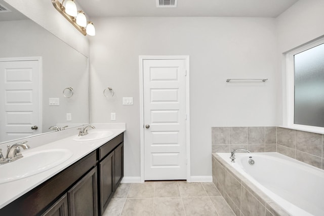 bathroom with a relaxing tiled tub, tile patterned floors, and vanity