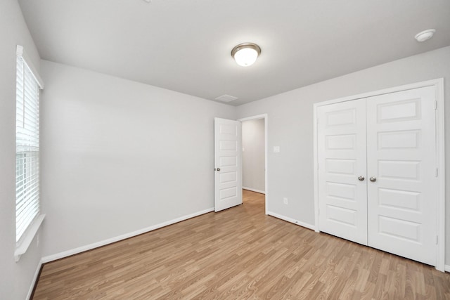 unfurnished bedroom with a closet, multiple windows, and light wood-type flooring