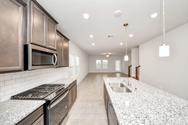 kitchen featuring light stone counters, hanging light fixtures, sink, and appliances with stainless steel finishes