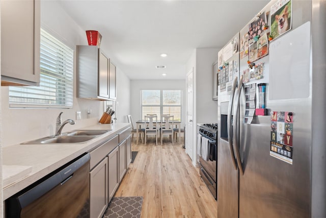 kitchen with visible vents, light countertops, light wood-style flooring, a sink, and black appliances