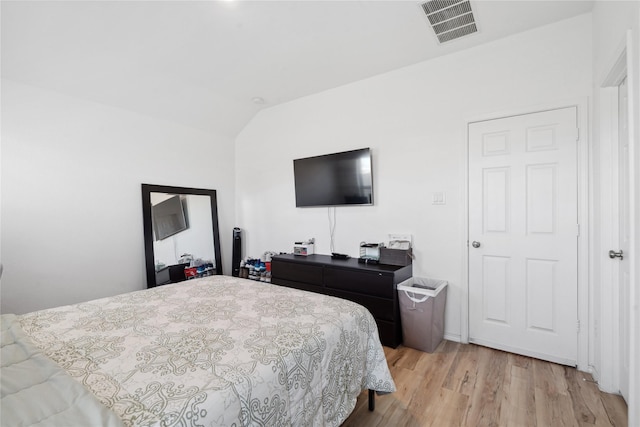 bedroom featuring vaulted ceiling, visible vents, and light wood-style floors