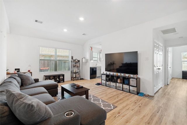 living room featuring visible vents, plenty of natural light, and light wood finished floors