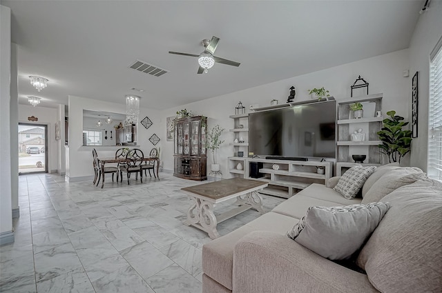 living area featuring ceiling fan with notable chandelier, marble finish floor, and visible vents