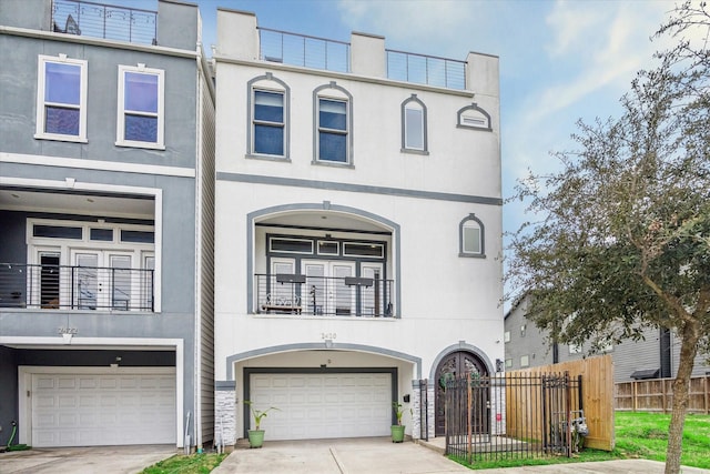 view of property with a garage, fence, concrete driveway, and stucco siding