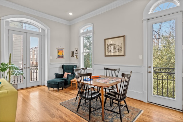 dining space with crown molding, light hardwood / wood-style floors, and french doors