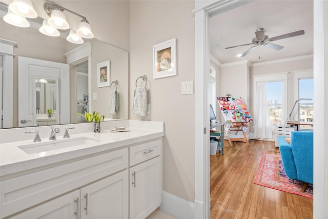 bathroom featuring ornamental molding, wood-type flooring, vanity, and ceiling fan