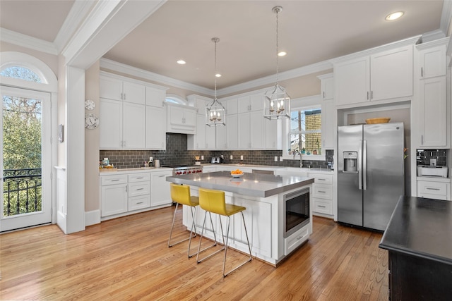 kitchen featuring white cabinetry, black microwave, crown molding, a center island, and stainless steel refrigerator with ice dispenser