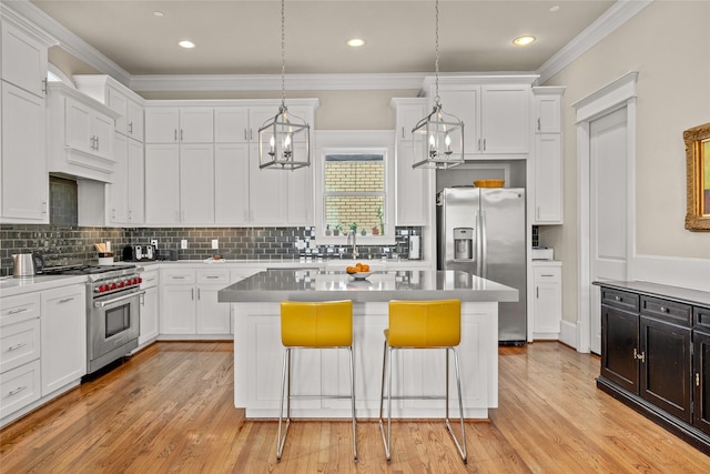 kitchen with a kitchen island, appliances with stainless steel finishes, white cabinetry, a kitchen bar, and crown molding